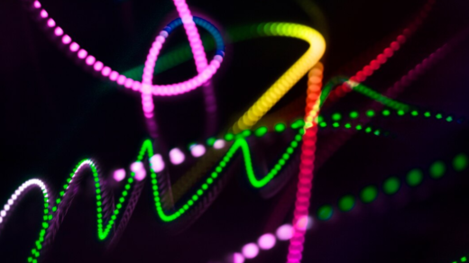 Vibrant, multicolored LED light trails form intricate swirling patterns in the dark