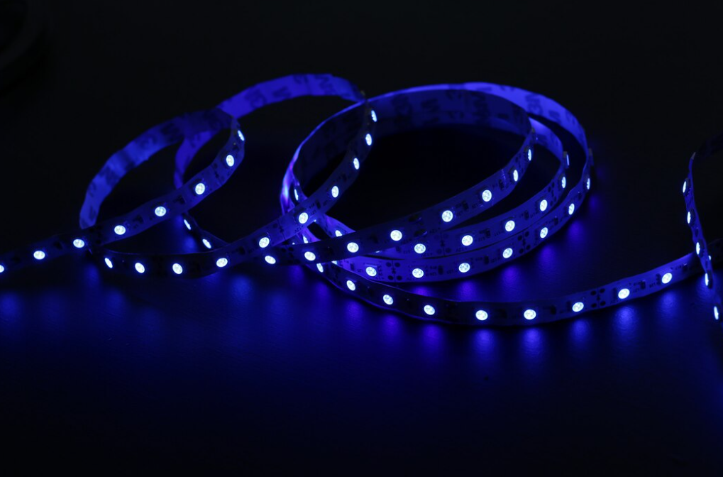 A coil of blue LED strip lights illuminates a dark surface with bright pinpoint dots