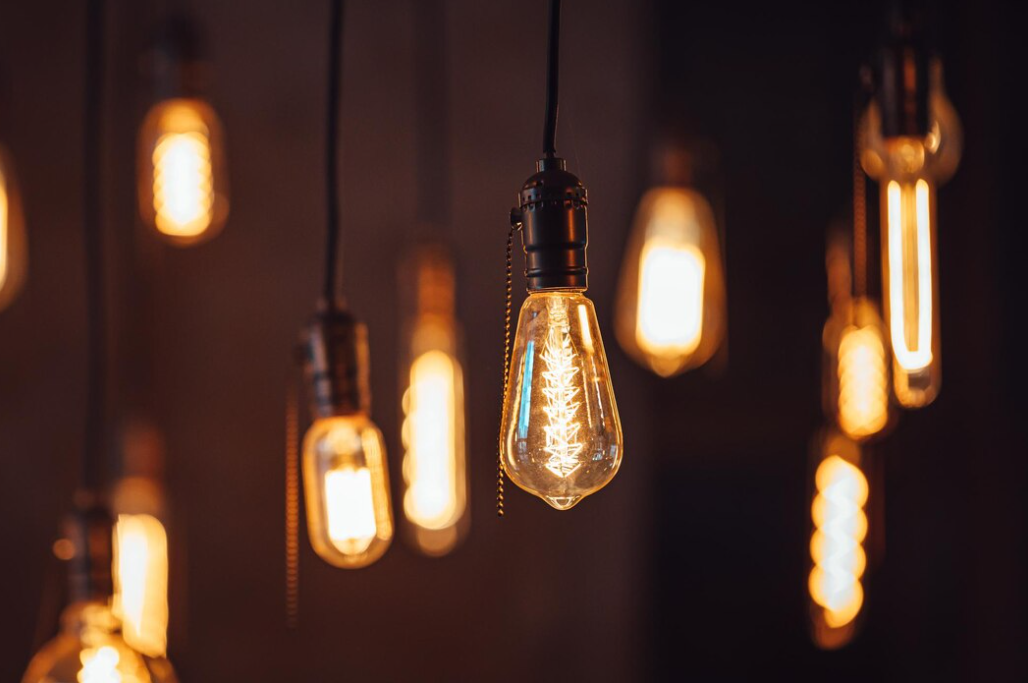 Vintage-style light bulbs hang from the ceiling, emitting a warm amber glow