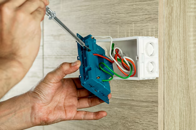 Hand holding disassembled socket on wooden wall