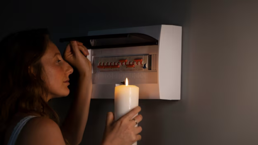 Woman with a candle in her hands checking an electrical panel