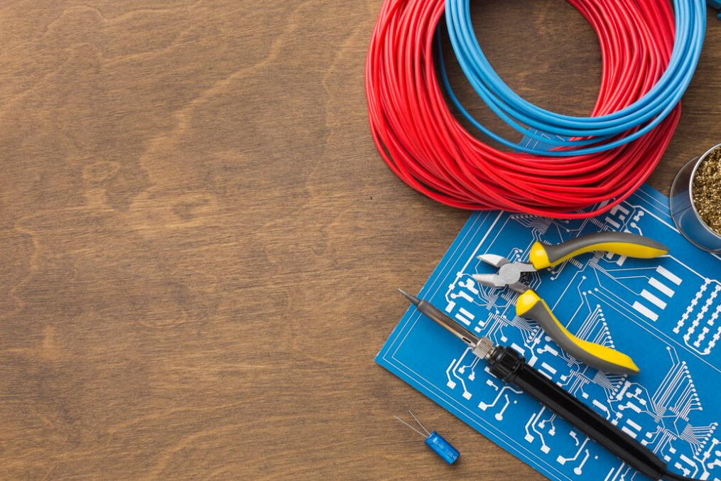 tools for repairing, red and blue wires, and circuit board on the wooden table