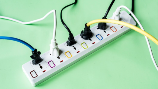 An overhead view of a white power strip with various cables plugged in, set against a vibrant green background