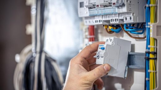 A close-up of a person's hand adjusting a modular electrical switch inside a circuit breaker panel