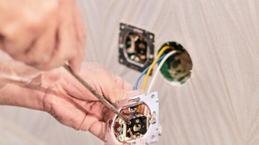hands of an electrician installing an electrical outlet