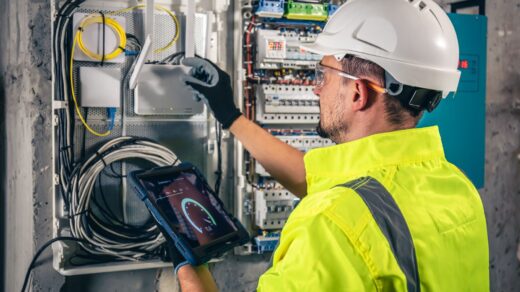 Electrical technician working in a switchboard with fuses uses a tablet