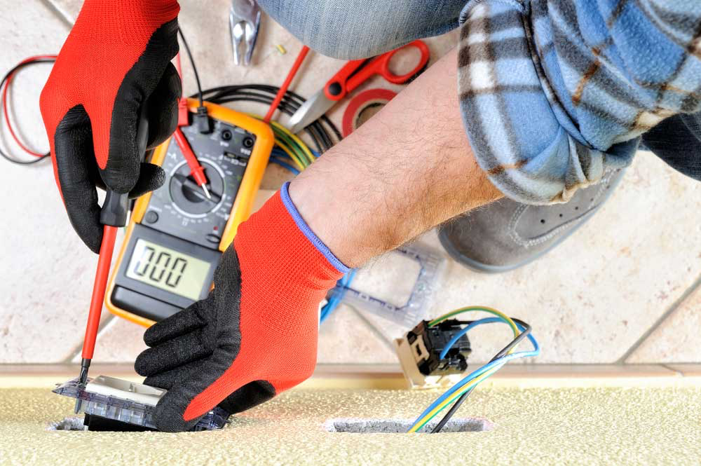 Hands in gloves hold a screwdriver and check the socket