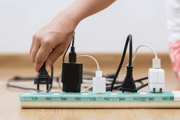 Hand plugs cord into surge protector